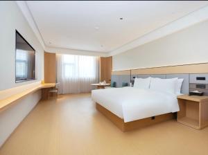 een slaapkamer met een groot wit bed en een televisie bij JI Hotel Suzhou Dushu Lake Ecological Park in Suzhou