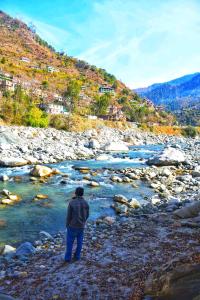 a man standing on the rocks near a river at Ivan homestay in Kulu +7 photos