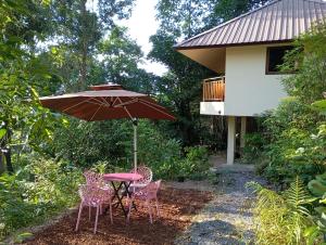 een tafel en stoelen onder een paraplu naast een huis bij Butterfly Cottage Tracy Island Had Yao in Ko Pha Ngan