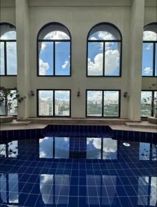 a room with a pool with windows and blue tiles at Apart Hotel Itaim Bibi in São Paulo