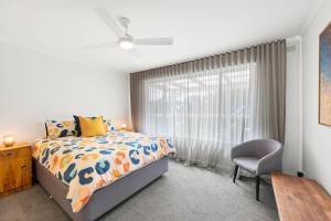 una camera da letto con un letto e una finestra con una sedia di Annelise a Lorne