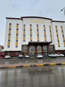 الجوهرة بارك 4 للشقق المخدومة في حفر الباطن: مبنى كبير به سيارات متوقفة في موقف السيارات