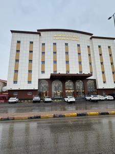 الجوهرة بارك 4 للشقق المخدومة في حفر الباطن: مبنى كبير به سيارات متوقفة في موقف السيارات