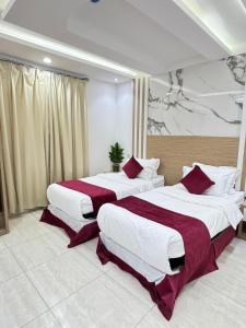 الجوهرة بارك 4 للشقق المخدومة في حفر الباطن: سريرين في غرفة في الفندق شراشف حمراء وبيضاء