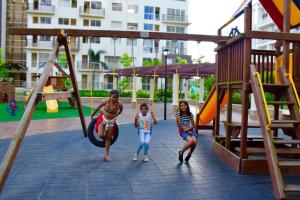 a woman and two children playing on a playground at Mondavi II Condo Unit 306 in Silang