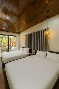 two beds in a room with two windows at Tam Coc Sora - Traditional Home - Center in Vũ Lâm