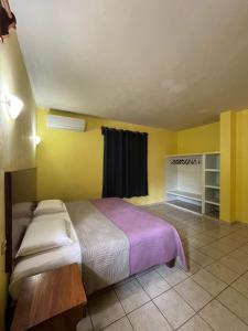 um quarto com uma cama num quarto com paredes amarelas em Casa ola Rinconada Piscina Starlink 5 min caminando a bahía Carrizalillo em Puerto Escondido