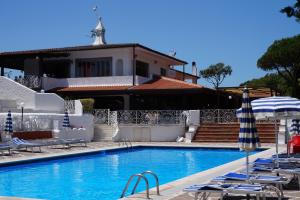 a swimming pool with lounge chairs and a house at Holiday Village in Fondi