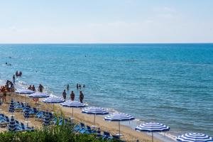 a beach with blue and white umbrellas and people in the water at Holiday Village in Fondi