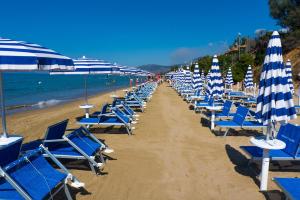 a row of chairs and umbrellas on a beach at Holiday Village in Fondi