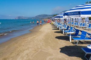 a beach with chairs and umbrellas and the ocean at Holiday Village in Fondi