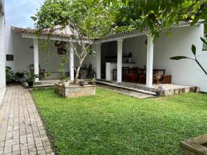 a white house with a lawn in front of it at Olympus House in Mirissa