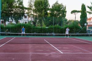 dos hombres jugando al tenis en una pista de tenis en Holiday Village, en Fondi