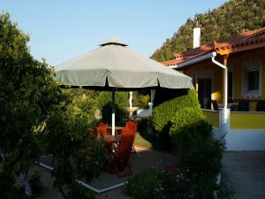 a table and chairs under an umbrella in front of a house at Elisabeth Villas in Kerveli