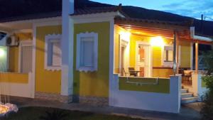 a house with a yellow and green facade at night at Elisabeth Villas in Kerveli