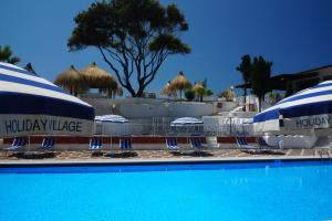 a pool with blue and white chairs and umbrellas at Holiday Village in Fondi
