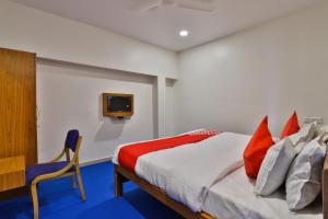 Un dormitorio con una cama y un televisor en una pared. en Hotel O Milan Party Hall, en Vadodara
