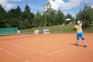 a man serving a tennis ball on a tennis court at Namelis šalia vynuogyno in Būdziliai