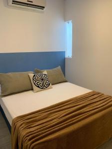 a bed with a brown blanket and pillows on it at Sobradinho Riviera, 3 Quadras do Mar - COM AR CONDICIONADO no quarto in Matinhos