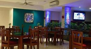 a restaurant with a table and chairs and a tv at Victoria Palms Hotel in The Domain