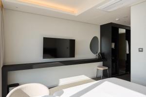 Un dormitorio con un televisor de pantalla plana en una pared. en Cov Stay Haeundae, en Busan