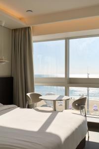 Habitación de hotel con 2 camas, mesa y ventana grande. en Cov Stay Haeundae, en Busan