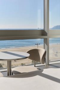 Una habitación con vista a la playa y una mesa y silla. en Cov Stay Haeundae, en Busan