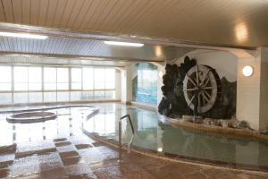 a swimming pool with a water wheel in a building at Ikaho Onsen Todoroki in Shibukawa