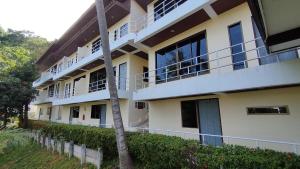 a building with balconies and a palm tree at Baan-kawkaew-kata in Ban Karon