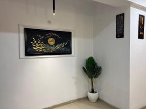 Stylish Comfort in the Heart of Dream Homes في غازي آباد: جدار أبيض مع صورة ونبات في أصيص +صورة واحدة