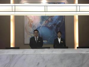 Magnotel Hotel Shanghai Railway Station Magnolia Plaza في شانغهاي: رجلان يرتديان بدلات يجلسان على طاولة