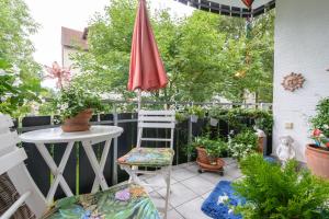 eine Terrasse mit einem Tisch und einem Regenschirm und einigen Pflanzen in der Unterkunft Wohnen bei Helga in Kassel