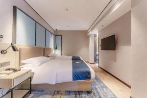 a bedroom with a bed and a desk and a television at Echarm Hotel Fuzhou Sanfang Qixiang East Street Metro Station in Fuzhou