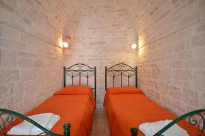 two twin beds in a room with a brick wall at I Trulli Di Ottavio in Alberobello