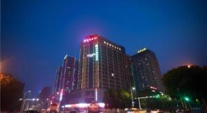 a tall building with red and green lights on it at City Comfort Inn Yichang Dongshan Three Gorges University Shuiyuecheng in Yichang