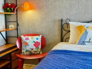 a bedroom with a bed and a red chair at 宜蘭頭城A Happy 享私人溫泉及大陽台 全景無邊際泳池 代辦騎馬 賞鯨 遊艇 私廚小吃等遊程 in Toucheng +76 photos