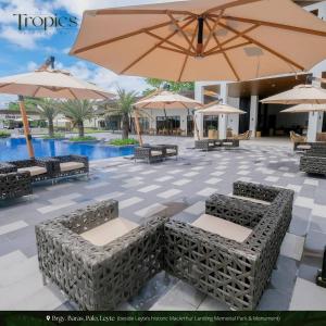 Un patio con sillas y sombrillas y una piscina. en The Tropics at MacArthur Park, en Palo