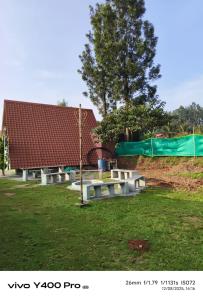 een groep picknicktafels in een park met een gebouw bij Green hut house in Yelagiri