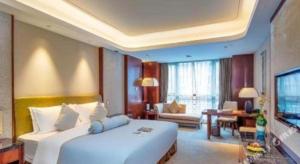 Days Hotel by Wyndham Hunan Changsha Convoy في تشانغشا: غرفة نوم بها سرير أبيض كبير وغرفة معيشة