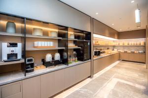 Una gran cocina con estantes de cristal y electrodomésticos. en JI Hotel Shenzhen Guangming Tianhuicheng, en Bao'an