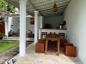 a patio with a wooden table and chairs at Olympus House in Mirissa