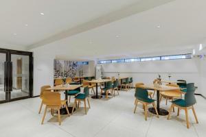 a dining room with wooden tables and green chairs at City Comfort Inn Yunfu Xinxing Juncheng Plaza in Xinxing