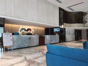 a lobby with a reception desk and a blue couch at Borrman Hotel Yunfu Xinxing County Bus Station in Xinxing
