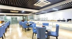 a restaurant with blue chairs and tables and a kitchen at Borrman Hotel Yunfu Xinxing County Bus Station in Xinxing
