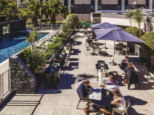 ポーにあるメルキュール ポー パレ デ スポーツのプールのあるパティオを歩く人々のグループ