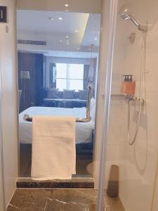 een badkamer met een douche en een bed met een handdoek bij Orange Hotel Suzhou Emerald Plaza in Suzhou