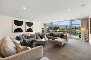 a large living room with couches and a large window at THE SHOTOVER Central Queenstown Luxury in Queenstown