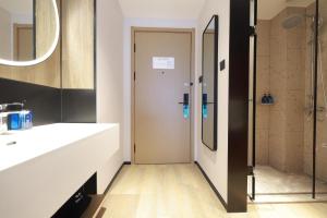 ein Badezimmer mit Dusche, Waschbecken und Spiegel in der Unterkunft Ni Hao in Houshayu