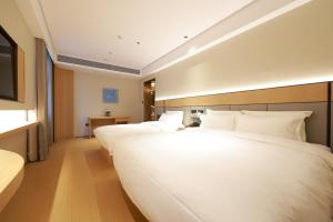 zwei große weiße Betten in einem Hotelzimmer in der Unterkunft Ni Hao in Houshayu