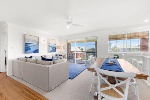 een witte woonkamer met een tafel en een bank bij Sommaroy - Pet Friendly with Fire Pit in Currarong